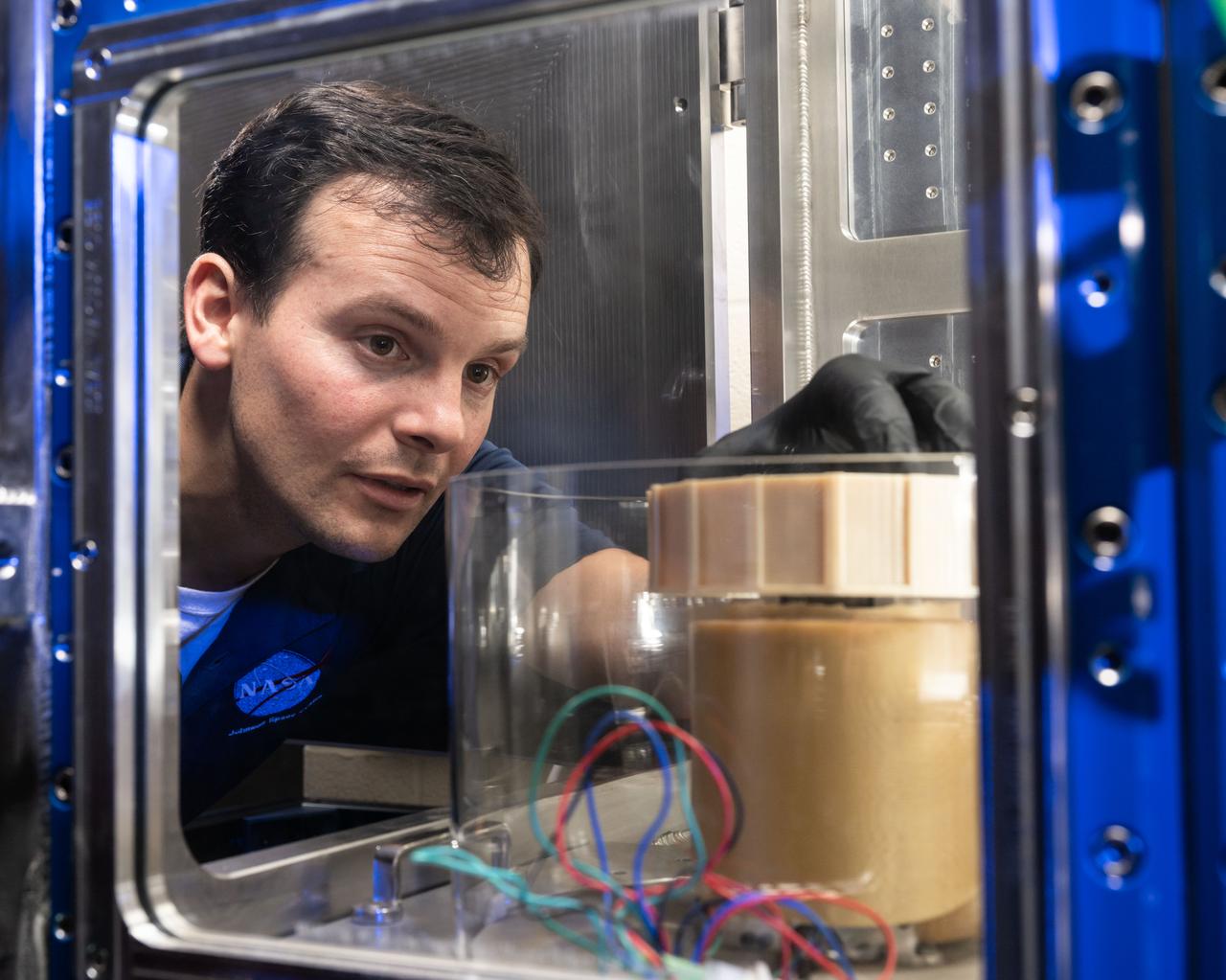 Josh Litofsky leads a Gateway lunar dust adhesion testing campaign at NASA’s Johnson Space Center in Houston. His team studies how lunar dust interacts with materials chosen for Gateway's construction. Here, Litofsky carefully positions a sample holder inside a vacuum chamber.   Litofksy’s work seeks to validate the Gateway On-orbit Lunar Dust Modeling and Analysis Program (GOLDMAP), developed by Ronald Lee, also of Johnson Space Center. By considering factors such as the design and configuration of the space station, the materials used, and the unique conditions in lunar orbit, GOLDMAP helps predict how dust may move and settle on Gateway’s external surfaces.